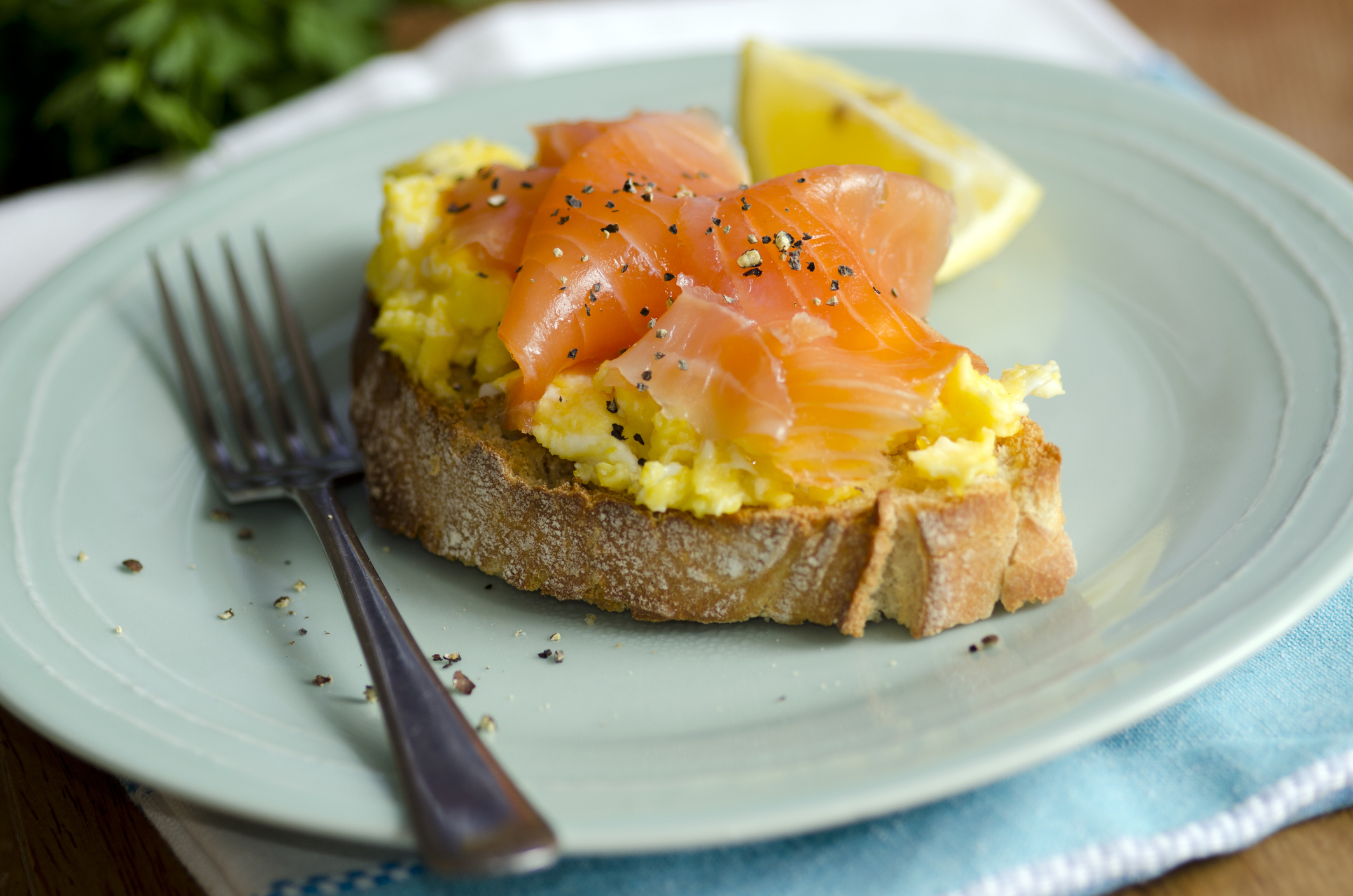 Smoked salmon and scrambled eggs on sourdough, with a lemon wedge